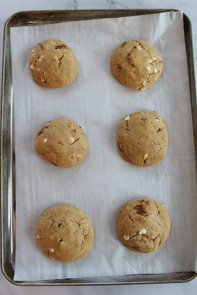 6 Cookie butter sourdough cookies baked on a parchment lined sheet pan.