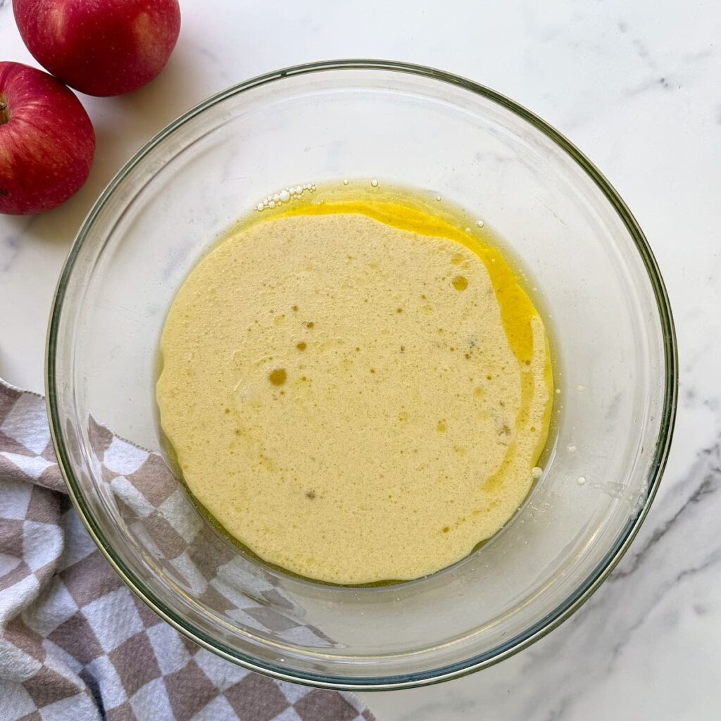 Wet ingredients for Sourdough Discard Apple Cake in a clear bowl.