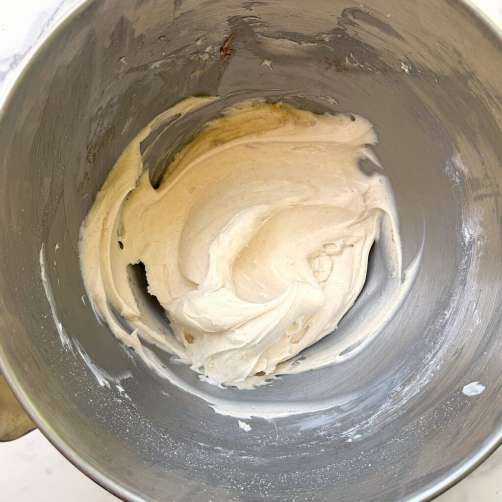 Cream cheese frosting mixed together in a stand mixer for sourdough discard apple cake.