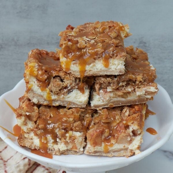 Sourdough Apple Cheesecake Bars stacked on top of each other on a white stand.