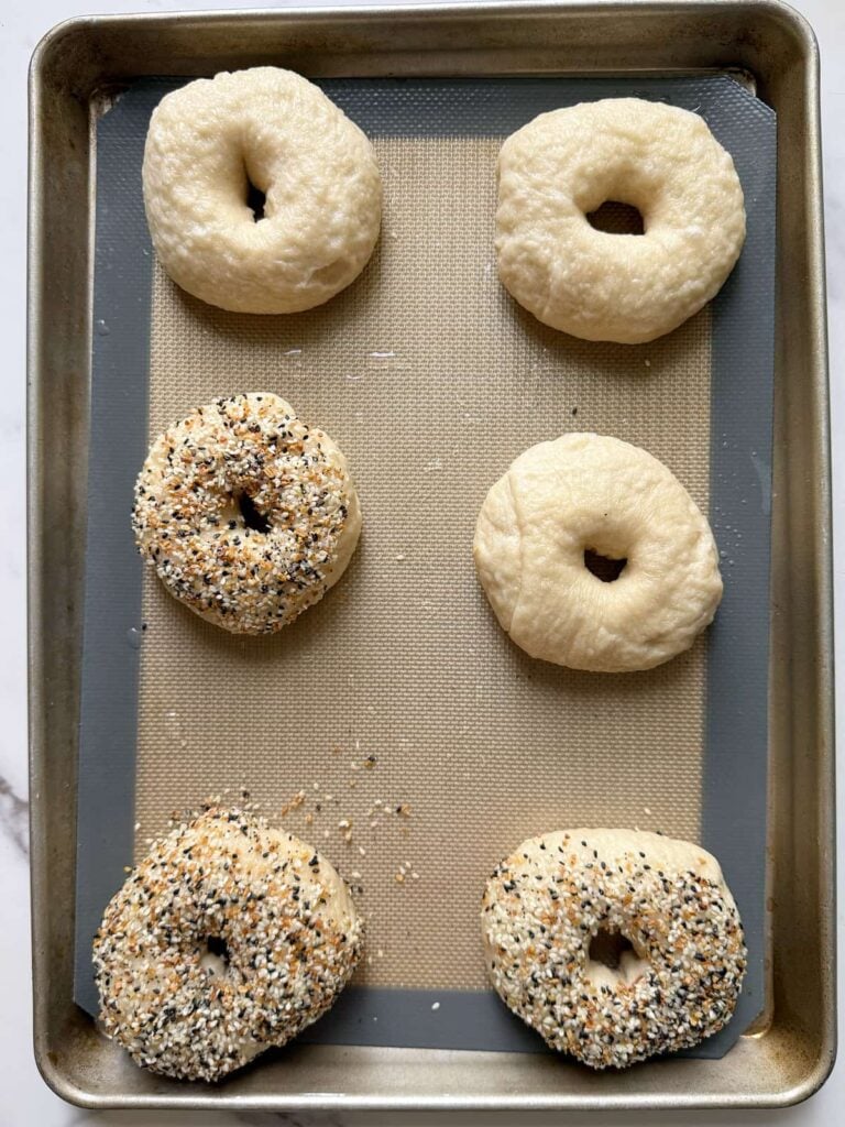 6 sourdough bagels on a sheet pan before baking.