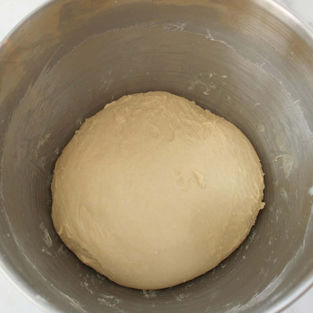 Sourdough dinner roll dough after kneading in a metal bowl before the first rise.