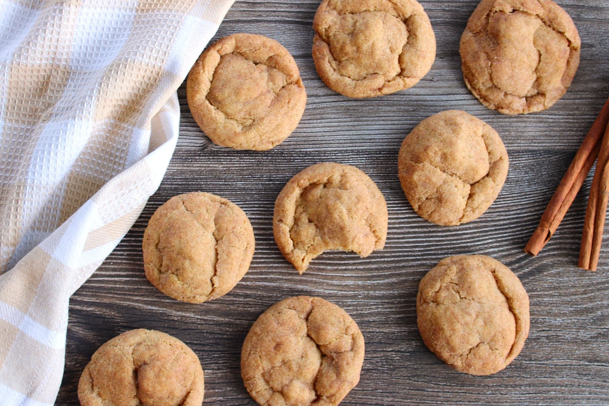 Sourdough Pumpkin Snickerdoodles on a wooden surface next to a brown and white cloth napkin.