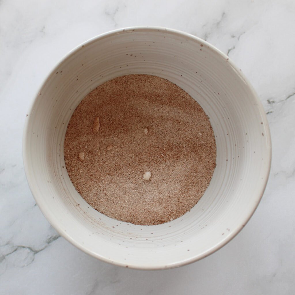 Cinnamon and sugar mixed together in a small white bowl.