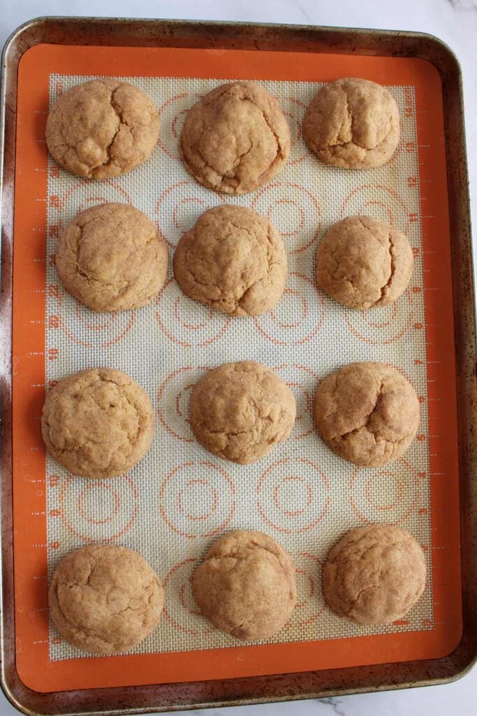 Freshly baked Sourdough Pumpkin Snickerdoodles on a sheet pan lined with a silicone baking mat.