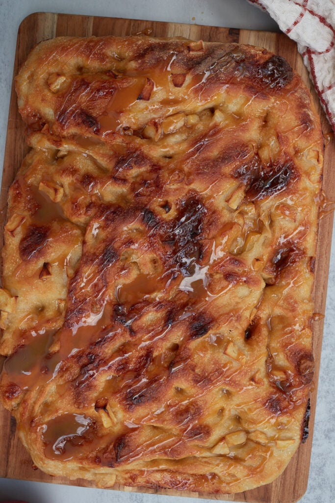 Caramel Apple Sourdough Focaccia on a wooden cutting board with a caramel drizzle.