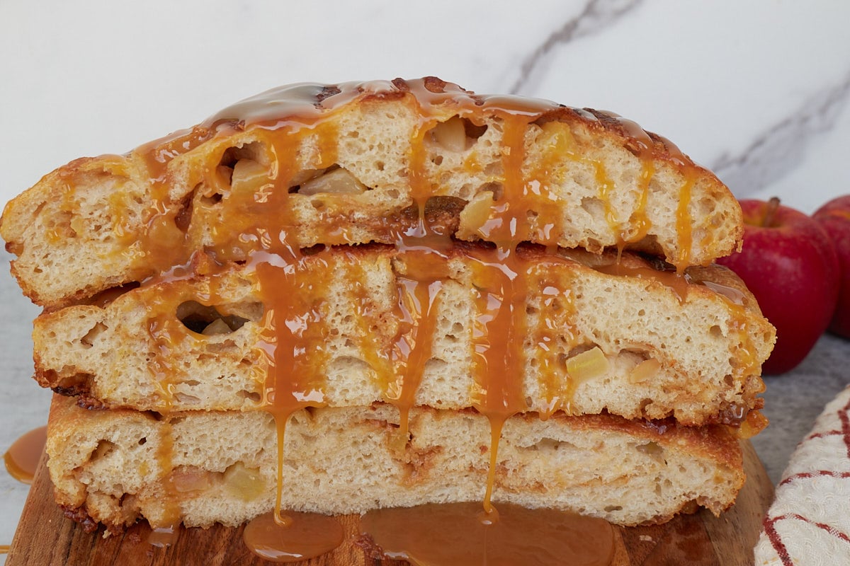 Three slices of Caramel Apple Sourdough Focaccia stacked on top of each other with caramel sauce drizzled on top.