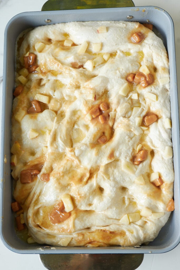 Caramel Apple Sourdough Focaccia dough with butter drizzled on top and dimples in the dough.