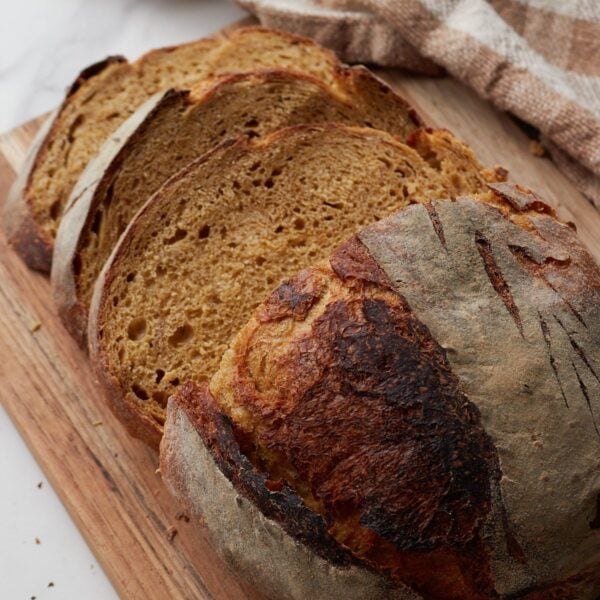 Artisan sourdough bread sliced on a wood cutting board.