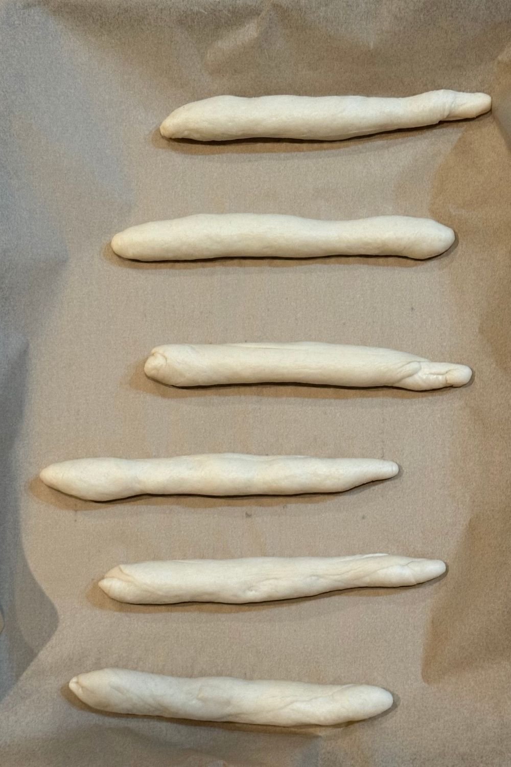 Sourdough breadstick dough shaped and place on a parchment-lined sheet pan.