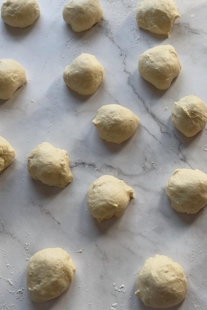 Sourdough dinner roll dough divided into 15 dough balls.