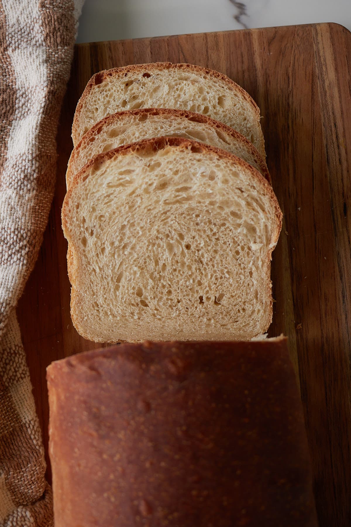 Sourdough Sandwich Bread Loaf sliced on a wooden cutting board.