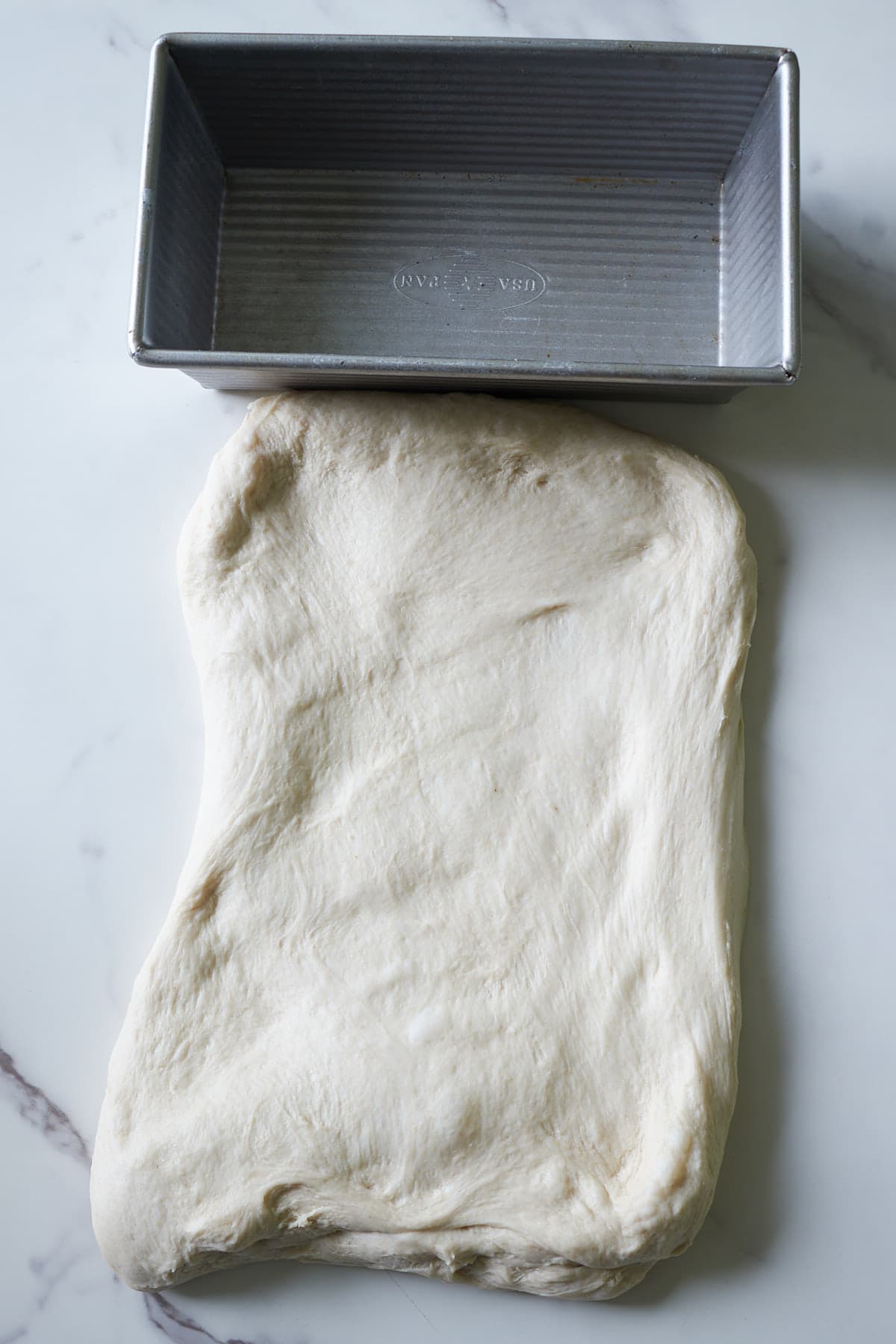 Sourdough Sandwich Bread Dough in a rectangle next to a loaf pan.