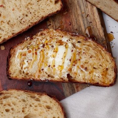 hot honey asiago sourdough bread slices with butter and drizzles in hot honey.