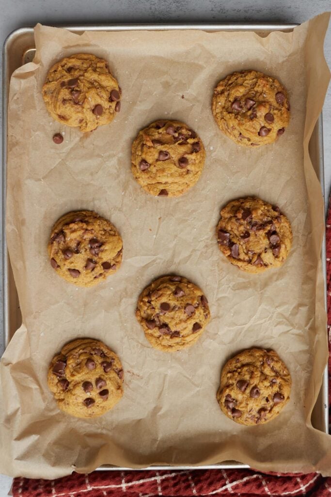 Sourdough pumpkin chocolate chip and heath bits cookies on a sheet pan with parchment paper.
