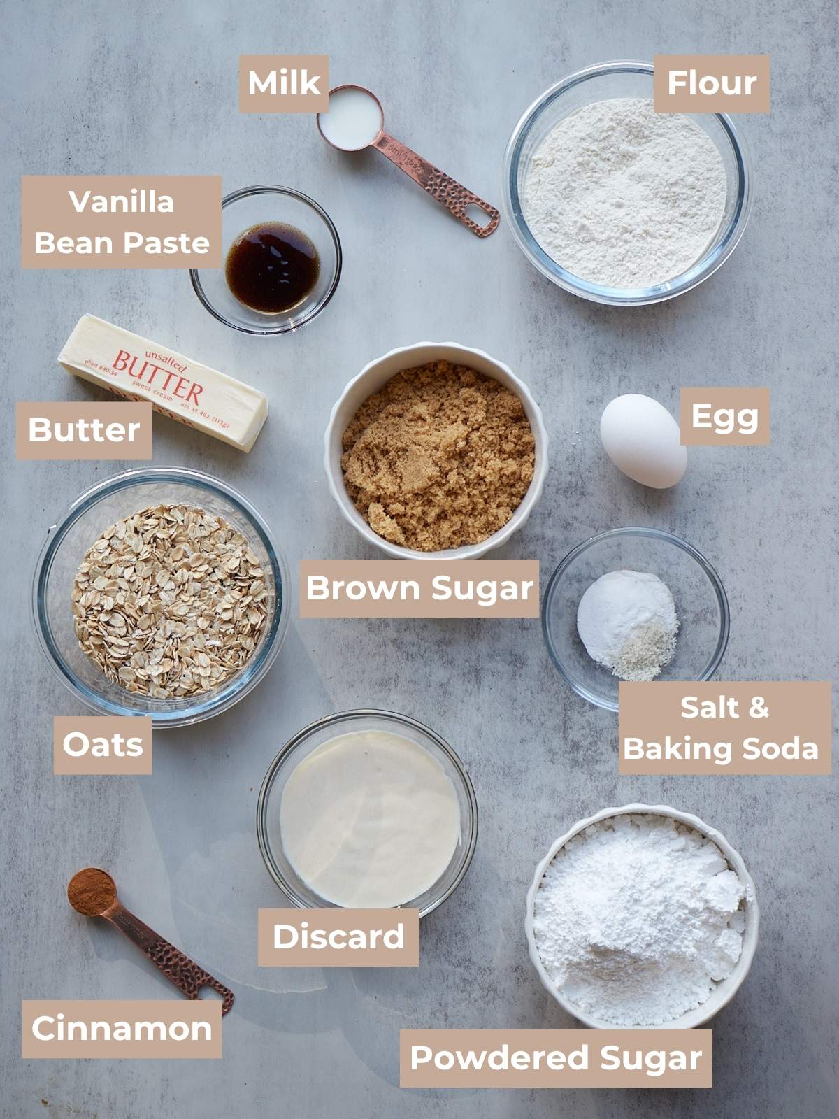 Ingredients for Sourdough Oatmeal Cookies in clear bowls on a grey background.