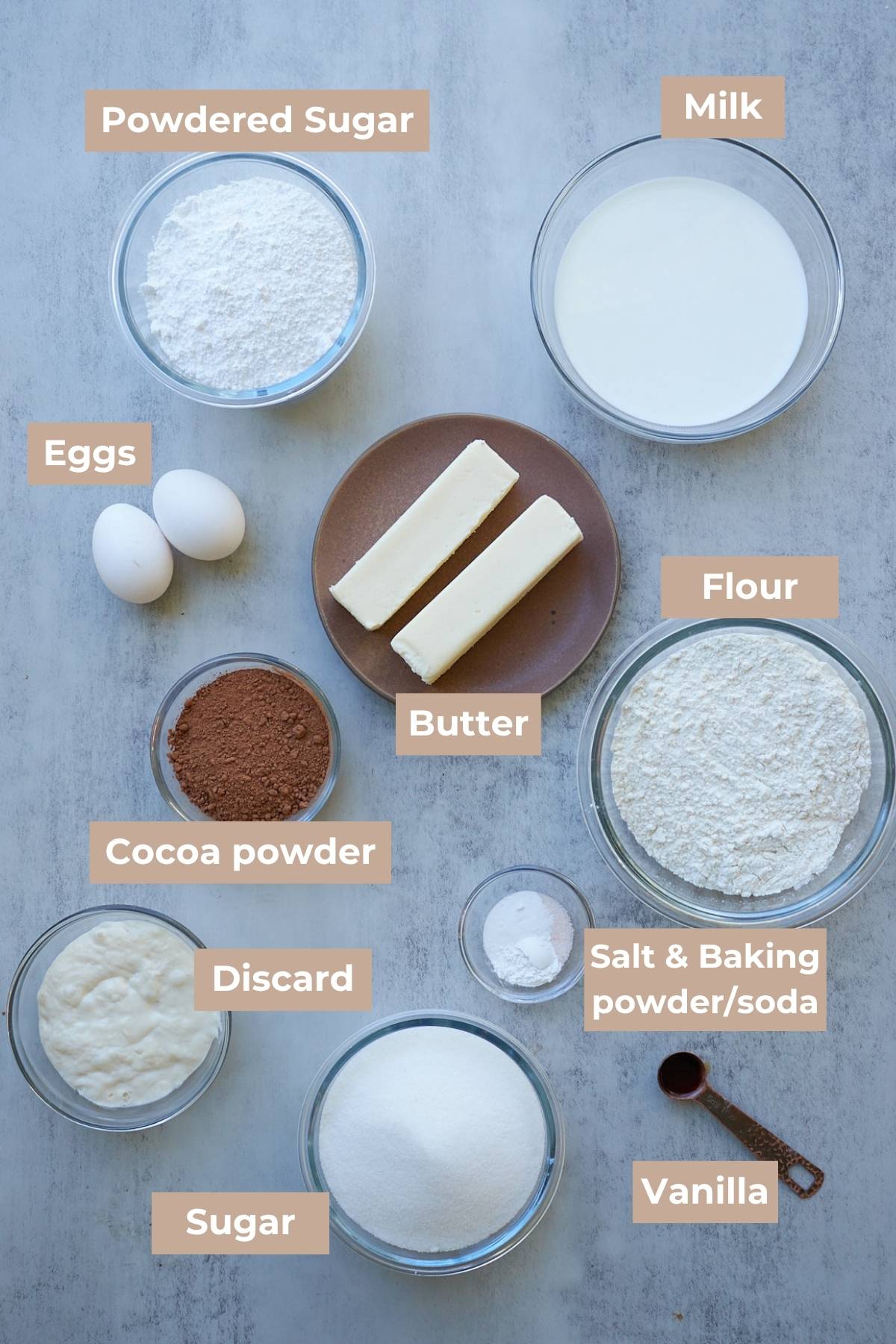 Ingredients for Sourdough Chocolate Cake in clear bowls on a grey background.