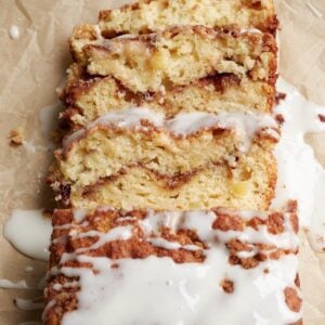 Slices of Sourdough Apple Fritter Bread with a vanilla glaze on a piece of brown parchment paper.