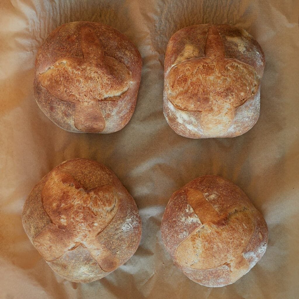 Freshly baked sourdough bread bowls on parchment paper.