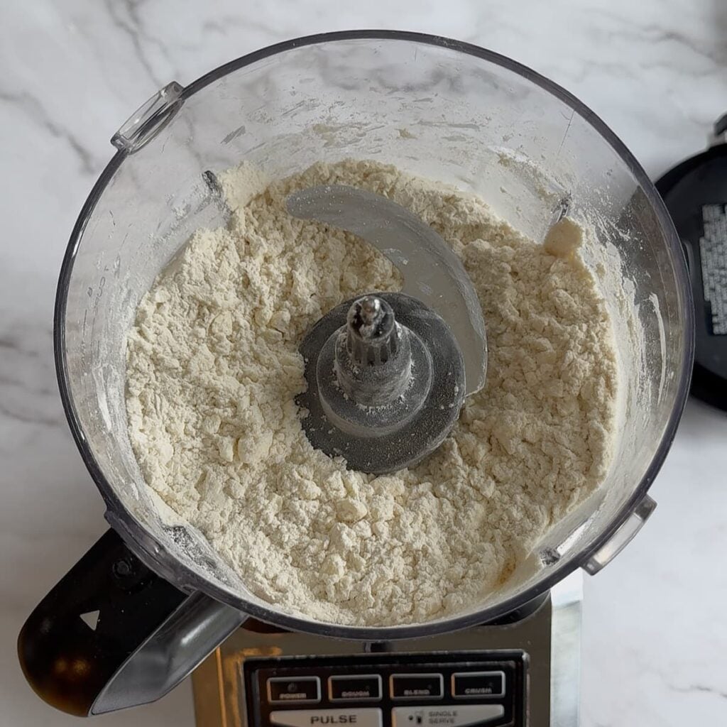 Butter, flour, salt, and baking powder in a food processor for Sourdough Cheddar Biscuits.