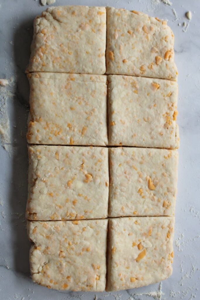 Sourdough Cheddar Biscuit dough cut into 8 squares.