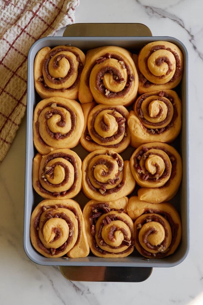 Sourdough pumpkin cinnamon rolls in a 9x13 pan after second rise.
