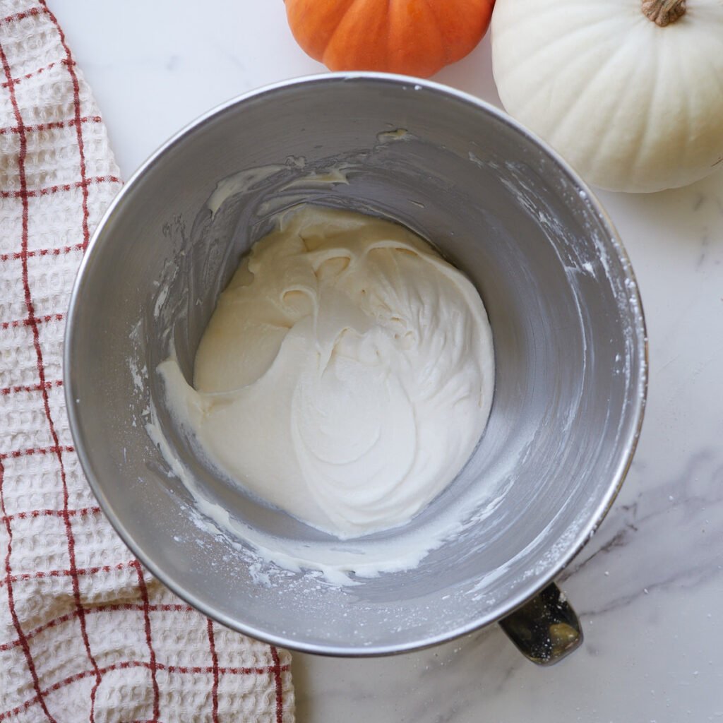 Cream cheese frosting mixed together in a metal bowl.
