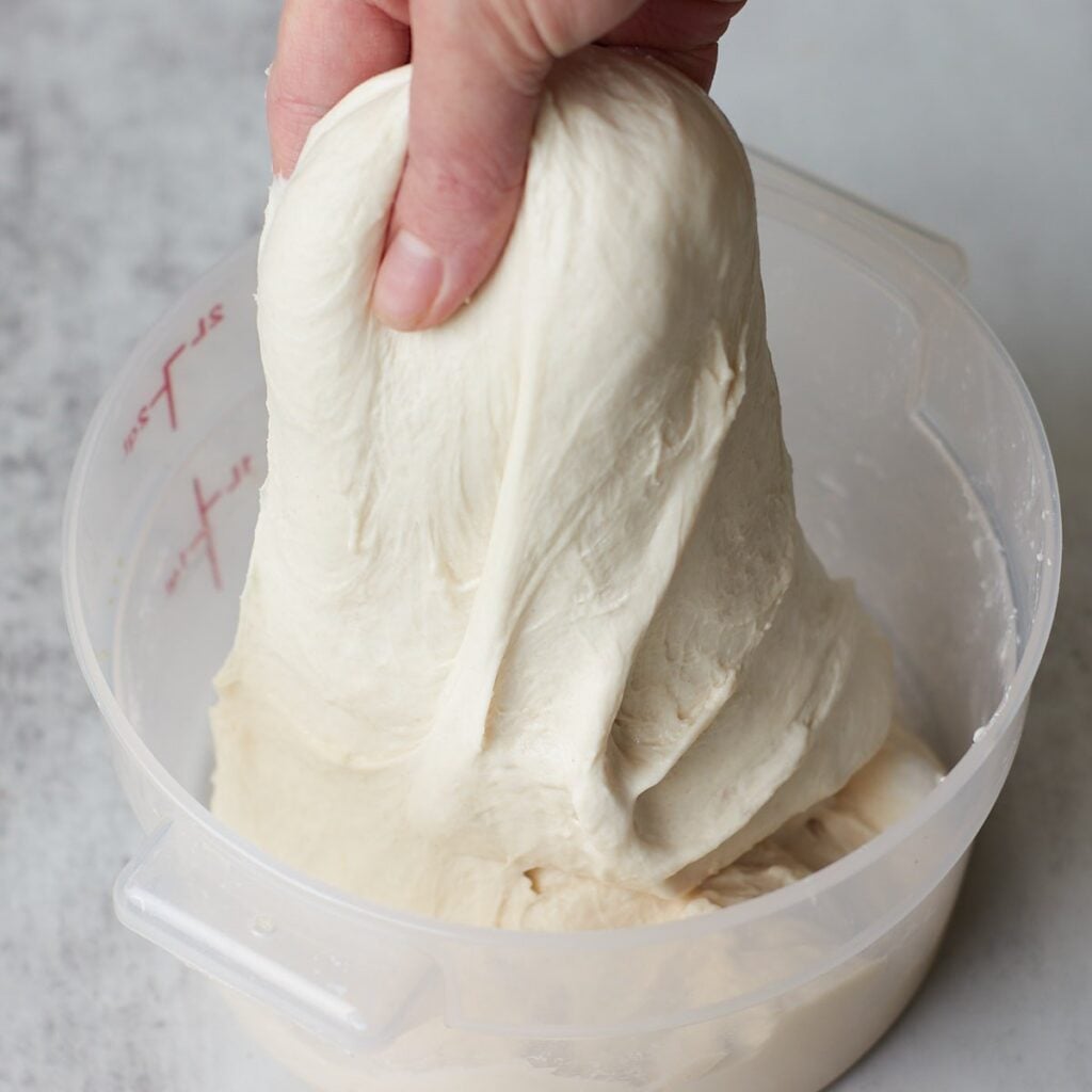 Hand pulling up dough to do a set of stretch and folds.