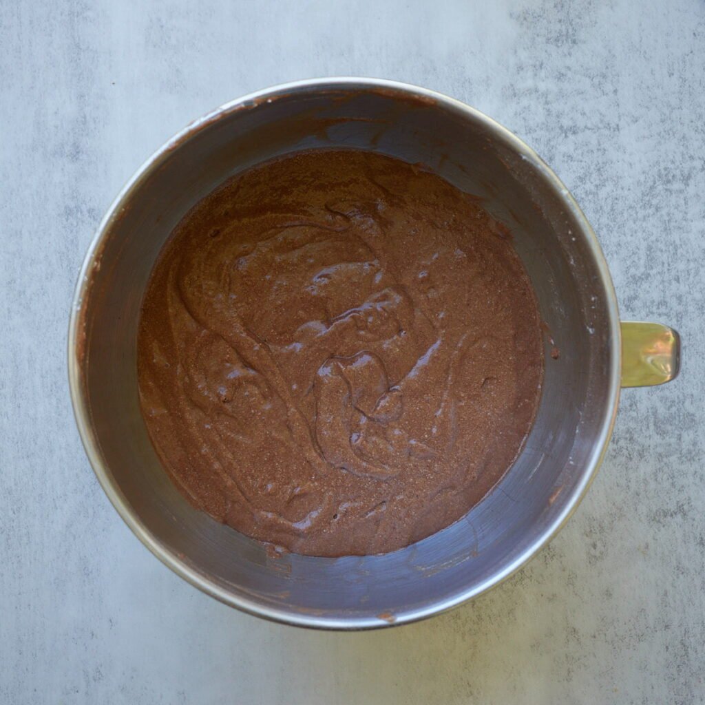 Dry ingredients added to the Sourdough Chocolate Cake batter in a metal bowl.