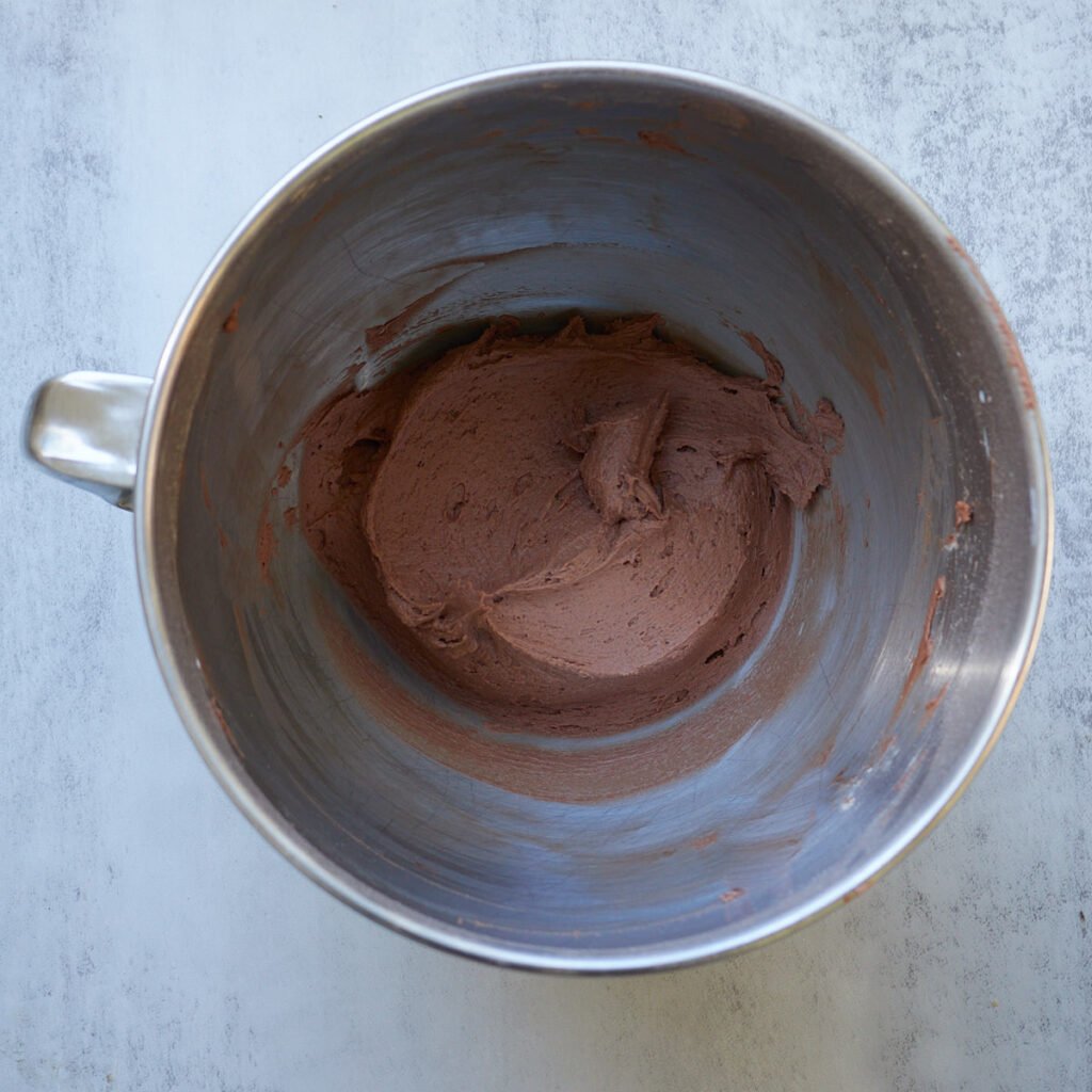 Chocolate buttercream frosting in a metal bowl.