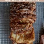 Sourdough Apple Pull-Apart Bread on a wire rack with a vanilla glaze with slices pulled out.