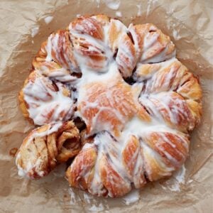 Sourdough Cinnamon Star Bread with cream cheese icing, with a section pulled off.