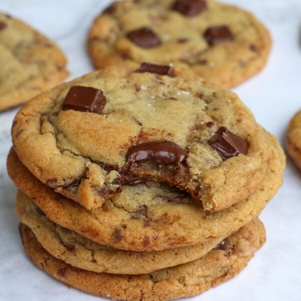 Sourdough Chocolate Chip Cookies stacked on top of each other with one bite taken out.