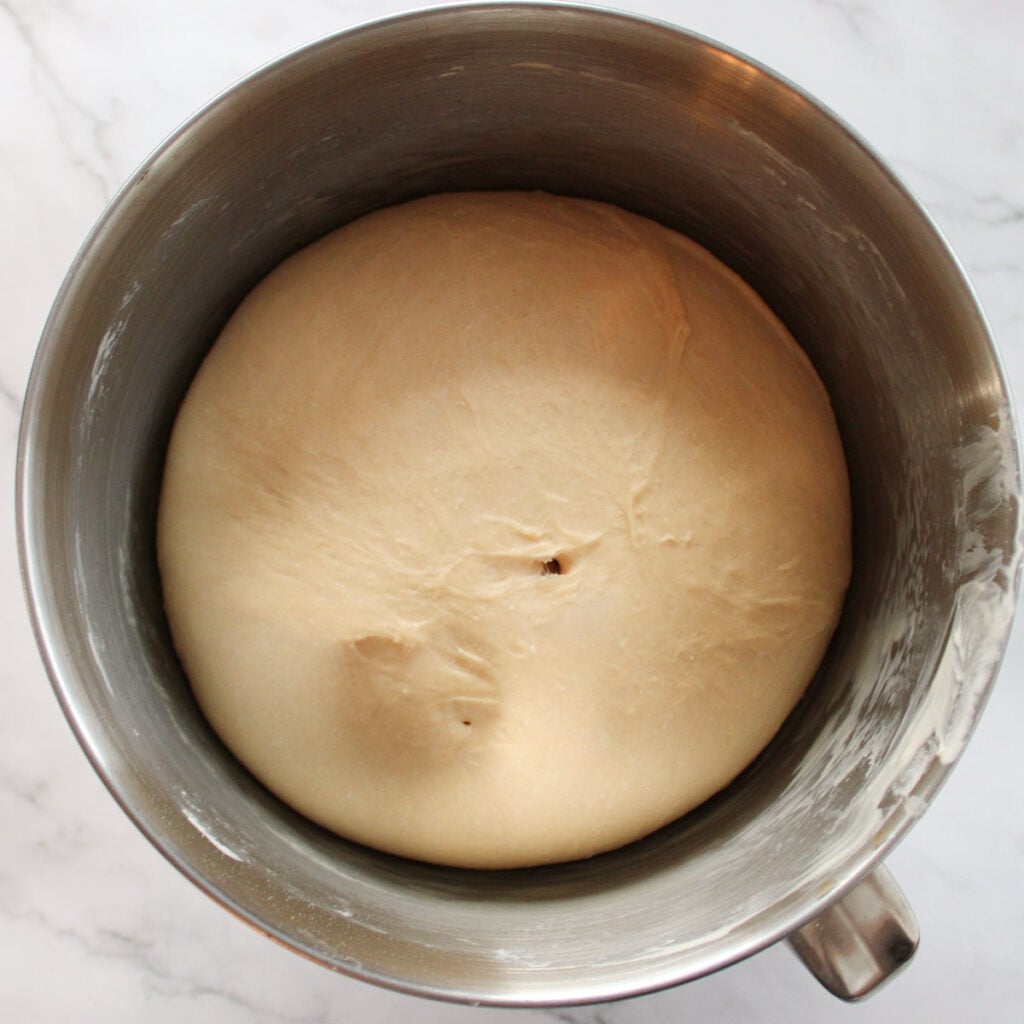 Sourdough Discard Hawaiian Roll dough after the first rise in a metal stand mixer bowl.