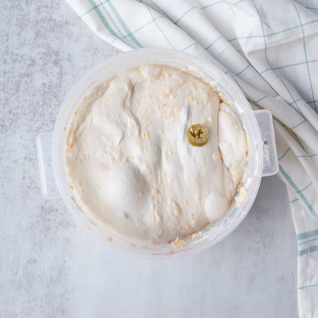 Jalape&ntilde;o Cheddar Sourdough Bread dough after bulk fermentation in a clear container.