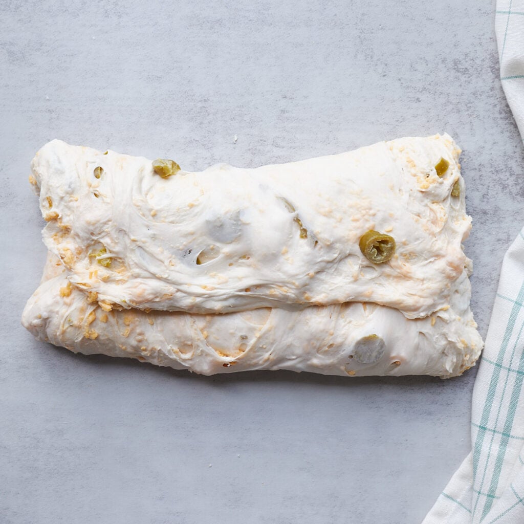 Jalape&ntilde;o Cheddar Sourdough Bread dough folded on top of itself during the shaping process.