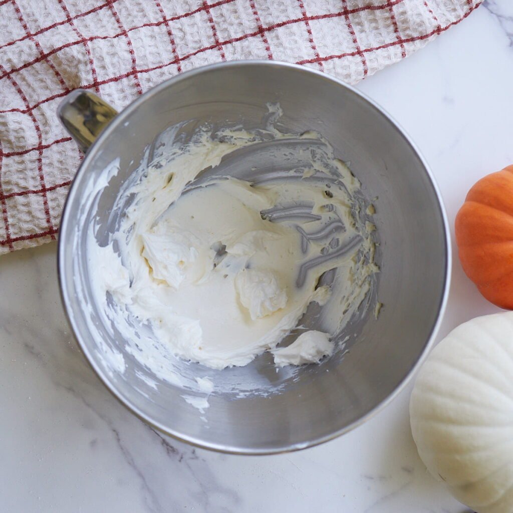 Cream cheese frosting mixed together in a metal bowl for a stand mixer.
