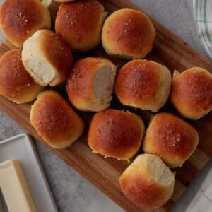 Sourdough Discard Dinner Rolls on a wooden board next to a stick of butter.