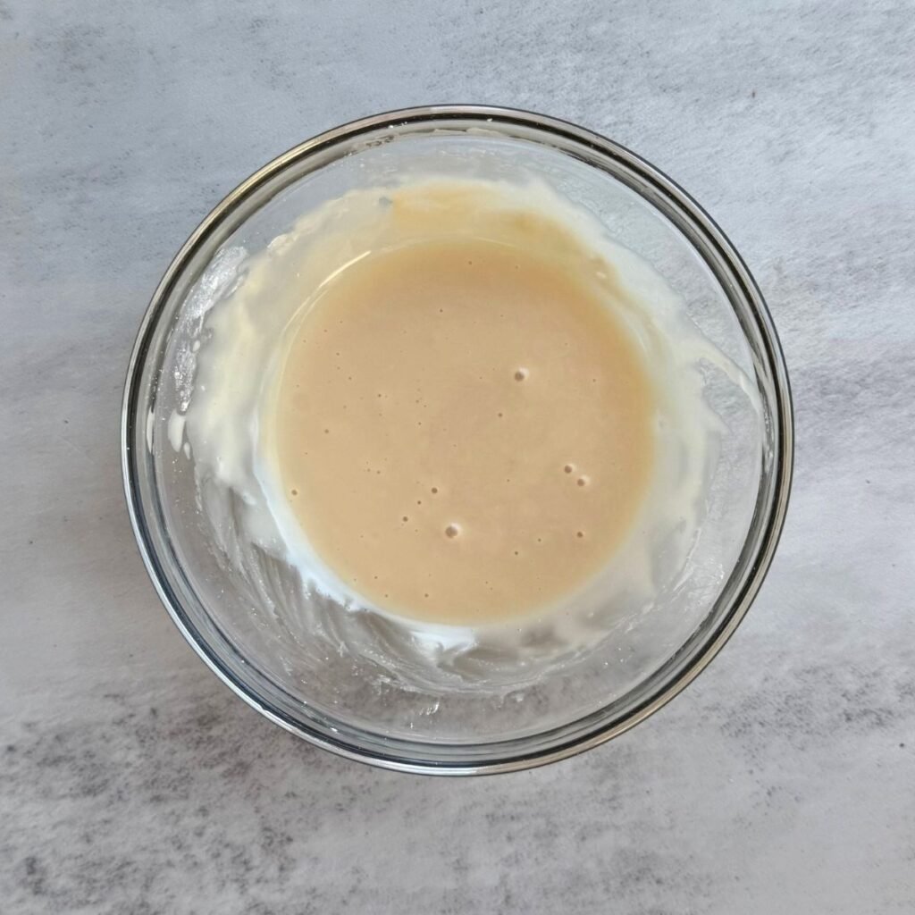 icing for sourdough apple pie pull apart bread in a clear bowl.