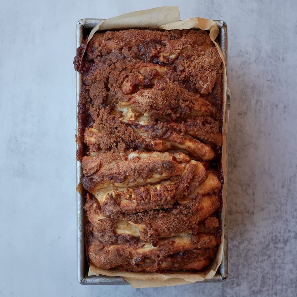 Freshly baked sourdough apple pie pull apart bread in a loaf pan.