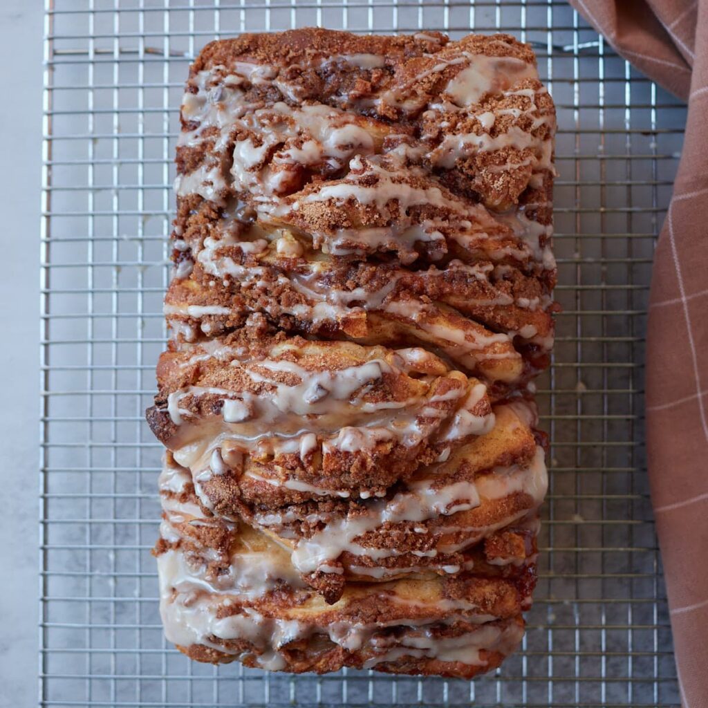 Sourdough Apple Pull-Apart Bread on a wire rack with a vanilla glaze.