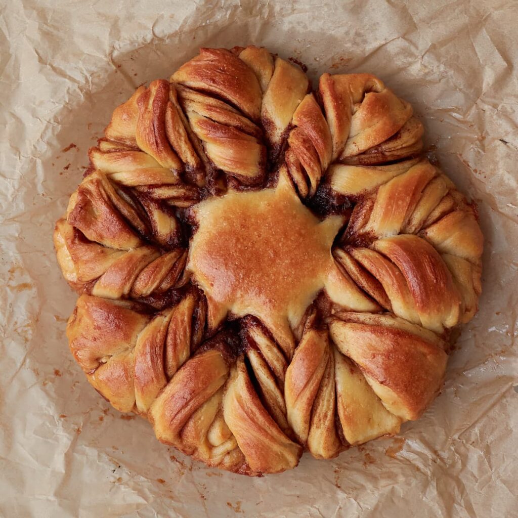 Freshly baked sourdough cinnamon star bread on parchment paper.