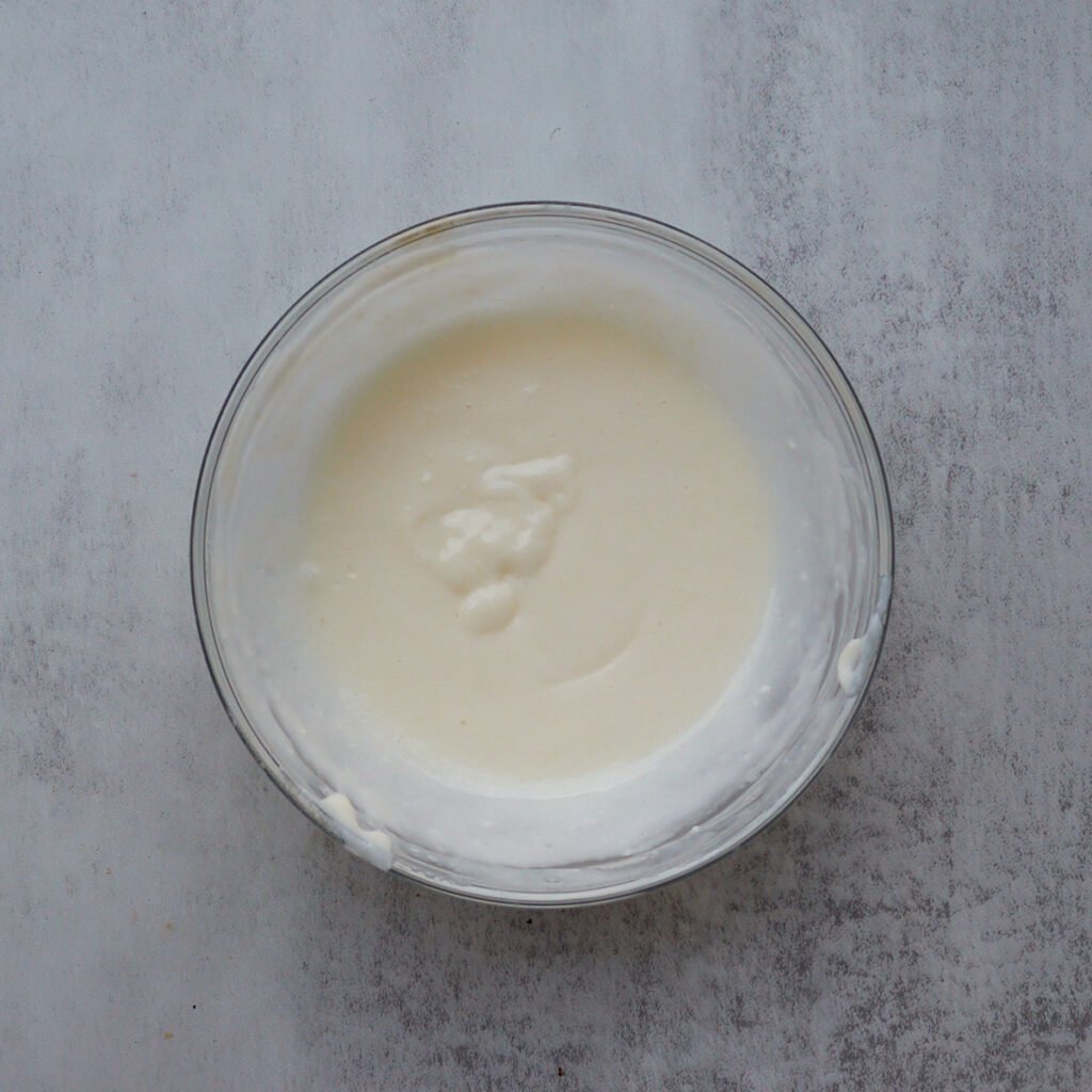 Cream cheese icing for sourdough cinnamon star bread in a clear bowl.