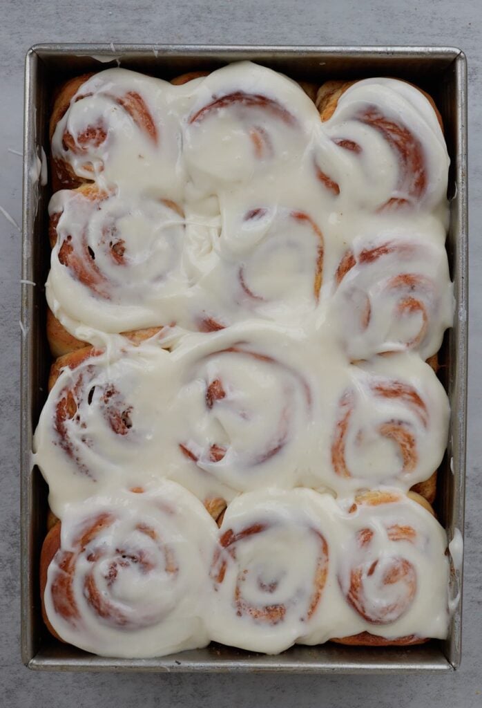 Frosting added to sourdough discard cinnamon rolls in a 9x13 pan.