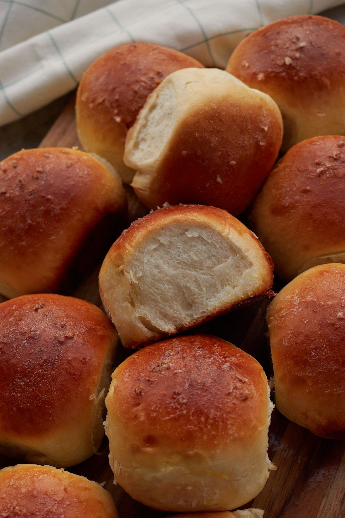Sourdough Discard Dinner Rolls on a wooden board with a white cloth napkin.