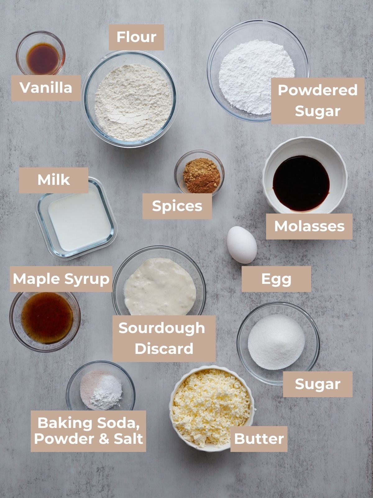 Sourdough gingerbread scone ingredients including butter, flour, spices, maple syrup, sourdough discard and other ingredients in glass bowls. 