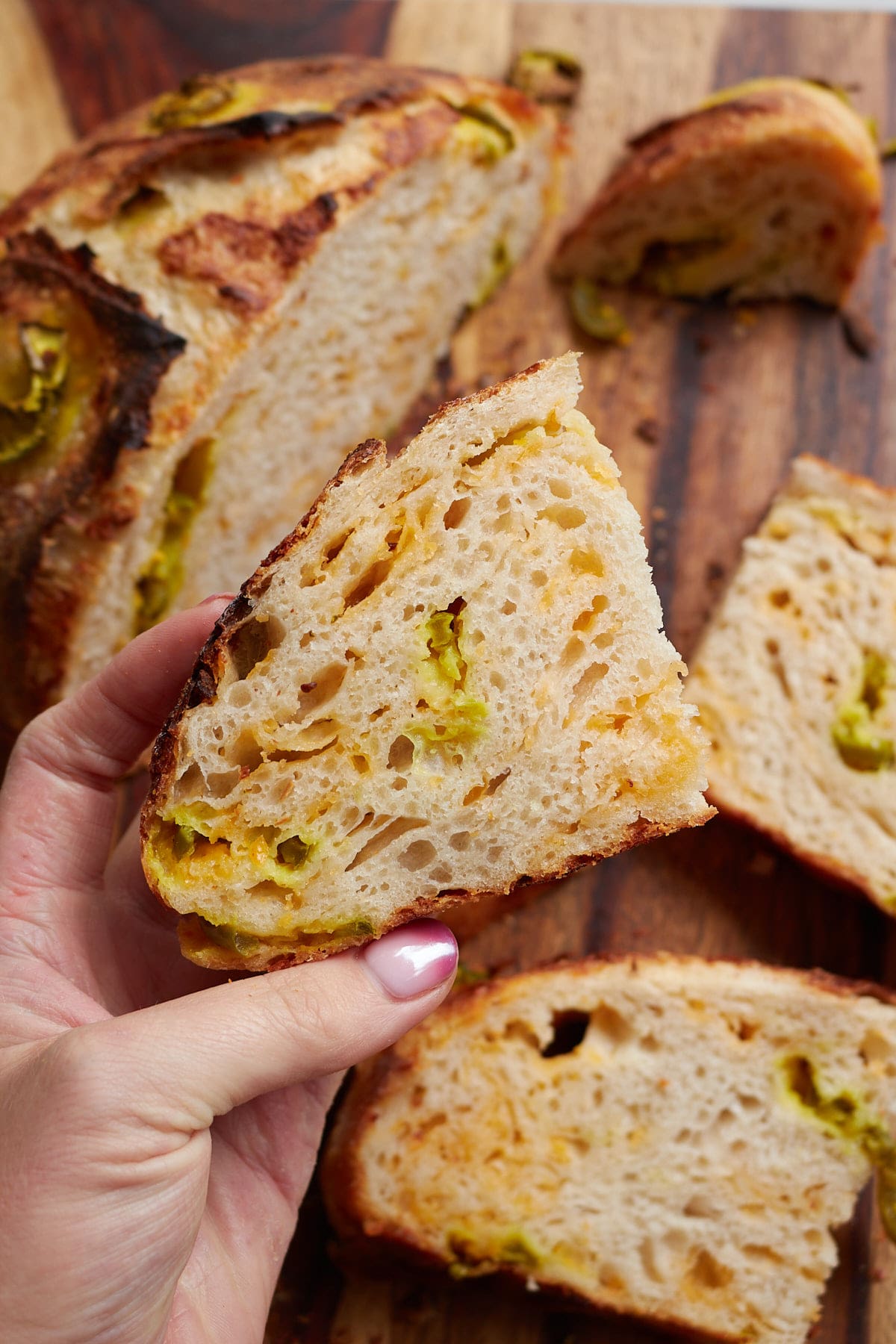 Hand holding a slice of Jalape&ntilde;o Cheddar Sourdough Bread.