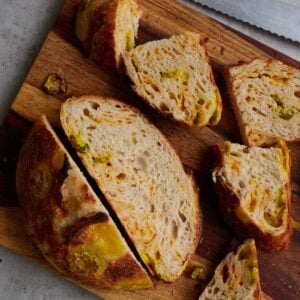 Jalape&ntilde;o Cheddar Sourdough Bread sliced on a wooden cutting board.