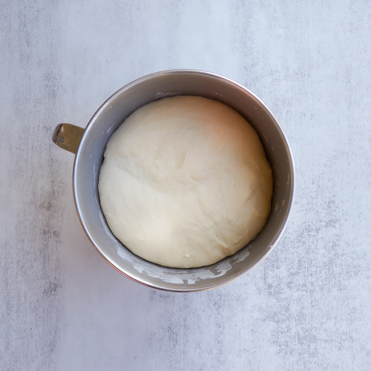 Sourdough sticky buns dough in a metal bowl after doubling in size.
