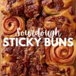 Sourdough sticky pecan buns on a wooden board with 2 sticky buns turned upside down to see the swirl.